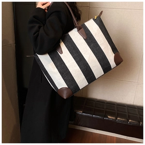 Grande borsa tote a righe bianche e nere con manici in pelle marrone indossata da una modella