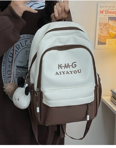 Detail view of contrast color backpack with embroidery and white plush pendant