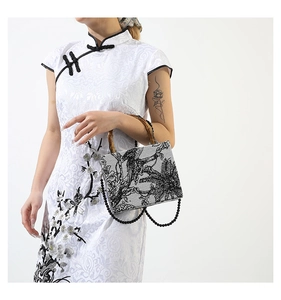 Detailed shot of fabric handbag featuring bamboo handles and traditional bird pattern