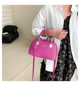 Détail du sac bandoulière fuchsia texturé lychee porté par un mannequin en jupe