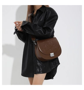 Détail d'un sac besace marron vintage avec motif étoile embossé sur surface en cuir