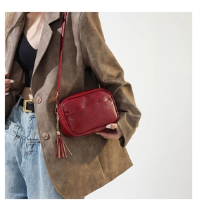 Detail of red quilted PU leather crossbody bag with fringe tassel on a model