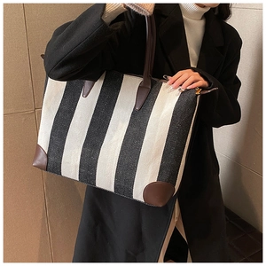 Dettaglio di una borsa tote in tela a righe con finiture in pelle marrone su una modella