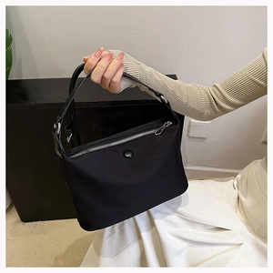 Detailed view of minimalist black nylon handbag with zip closure and top handle