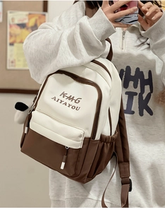 Detail view of two-tone nylon backpack showing front zipper pocket and embroidered logo