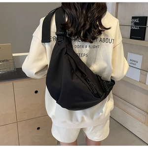 Rear view of model wearing a large black nylon crossbody bag in casual sporty style