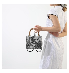 Detail of retro fabric handbag with bamboo handle and beaded chain on elegant model