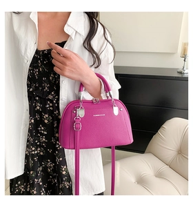 Détail du sac bandoulière fuchsia avec texture litchi et finitions métalliques argentées