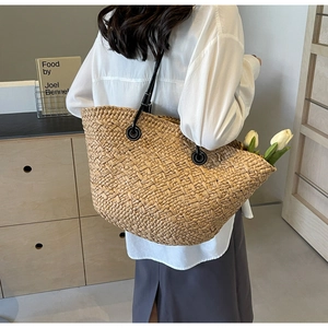 Gros plan d'un grand sac cabas en paille avec bandoulières en cuir noir et tulipes