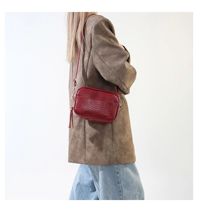 Detailed view of deep red chevron quilted PU leather crossbody bag with tassel detail
