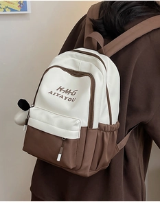 Detail of color-block backpack with letter print and plush pendant on adjustable straps