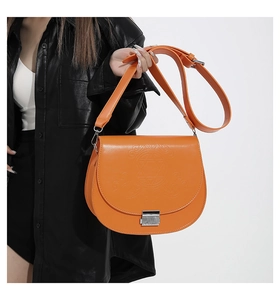 Détail d'un sac besace orange avec motif géométrique embossé et boucle en métal argenté