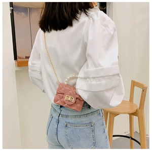 Mini sac en gelée rose avec poignée en perles et bandoulière dorée porté par un mannequin