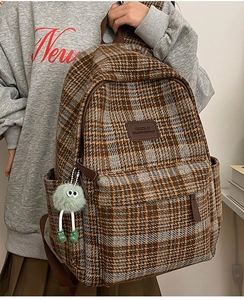 Détail d'un sac à dos vintage à carreaux avec écusson en cuir et charmant porte-clés en peluche