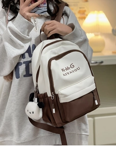 Detail view of stylish cream and brown canvas backpack with cute plush panda charm accessory