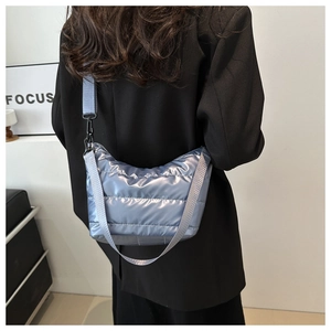 Detail of light blue quilted crossbody bag with metallic sheen and nylon shoulder strap