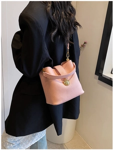 Détail du sac seau rose en cuir grainé avec pendentif en métal doré élégant