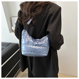Macro detail of glossy blue quilted puffer bag with sleek black metallic carabiner