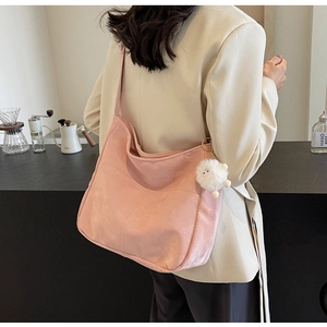 Pink large-capacity PU shoulder bag with white plush charm shown in a cozy cafe setting
