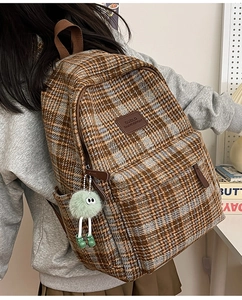Détail d'un sac à dos vintage à carreaux avec logo en cuir marron et pendentif en peluche