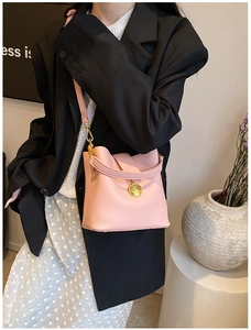 Vue détaillée du sac seau rose en cuir grainé avec emblème doré sur l'épaule