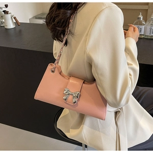 Dettaglio borsa baguette in pelle PU rosa con fiocco in metallo argento e tracolla a catena