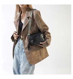 Detail of black faux leather crossbody bag with V-quilted stitching and ethnic wide strap