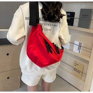 Model wearing a large red crescent nylon crossbody bag with adjustable wide black strap