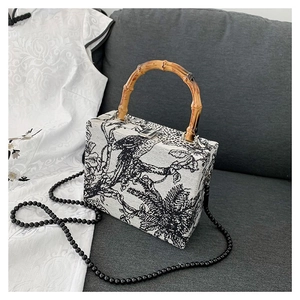 Retro square tote bag with floral bird print, bamboo handle and bead strap on sofa