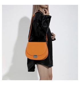 Détail d'un sac besace orange vif avec texture cuir mat et fermoir métallique carré