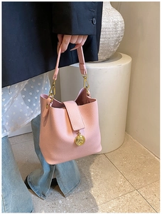 Détail du sac seau rose en cuir grainé avec pendentif en métal doré élégant