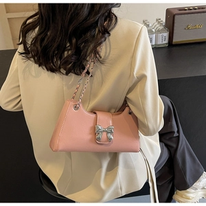 Dettaglio di borsa rosa in pelle PU con fibbia a fiocco argento e tracolla a catena