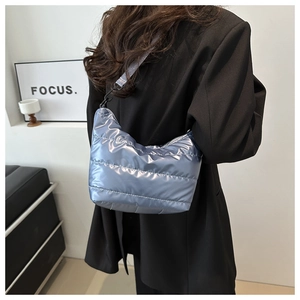 Detail of silver metallic quilted shoulder bag with adjustable strap on black blazer