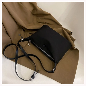 Minimalist black nylon crossbody bag with adjustable strap on a neutral background