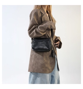 Detail view of black PU leather crossbody bag with V-quilted pattern and stylish long fringe