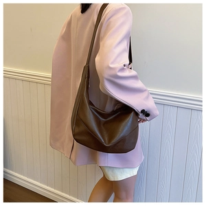 Detail view of the deep brown crescent moon bag with textured leather and metal zipper