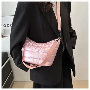 Detail of pink quilted puffer crossbody bag with adjustable strap on black blazer