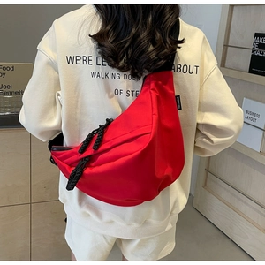Detail view of red canvas crossbody bag with thick rope zippers and nylon shoulder strap