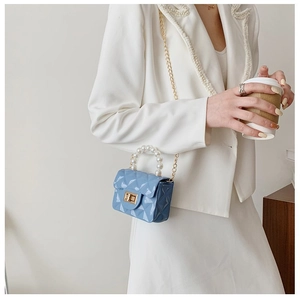Détail d'un mini sac gelée bleu clair avec poignée en perles et chaîne dorée sur mannequin