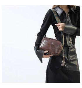 Detail of brown faux leather crossbody bag with V-quilt pattern and ethnic strap