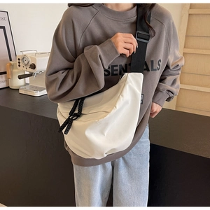 Close-up of cream nylon crescent crossbody bag with thick black woven zipper pull