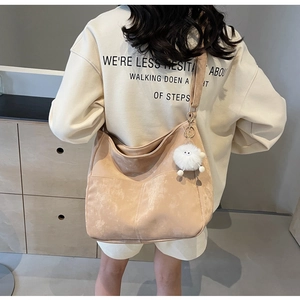 Detailed view of apricot minimalist PU crossbody bag with wide strap and plush ball charm