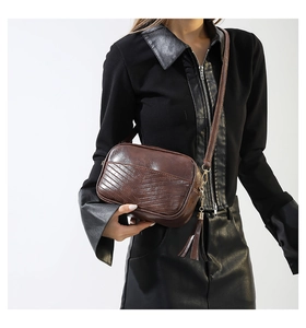 Detail of dark brown retro crossbody bag with V-quilt stitching and leather fringe tassel