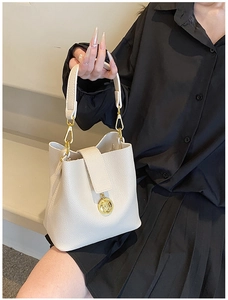 Détail du sac seau blanc cassé avec texture litchi et pendentif en métal doré