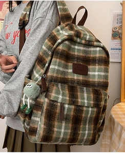 Détail d'un sac à dos à carreaux verts avec étiquette de marque et breloque monstre