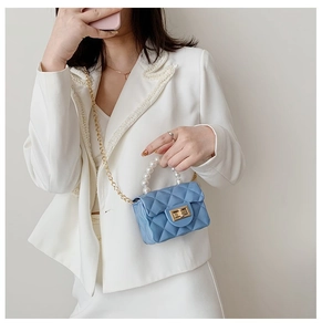 Détail du mini sac bleu clair avec poignée en perles et bandoulière en chaîne dorée