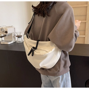Chic cream-colored nylon crescent bag with woven rope detail in a coffee shop setting