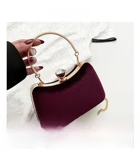 Detail of burgundy velvet clutch with gold metal ring handle and crystal clasp closure