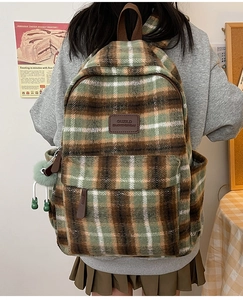 Détail d'un sac à dos en peluche à carreaux verts avec porte-clés monstre mignon