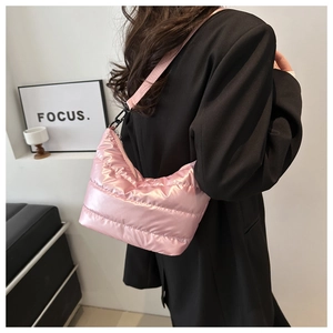 Detail of pink metallic puffer shoulder bag with quilted texture on model in black suit
